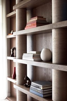 a bookshelf filled with lots of books next to a white vase and window