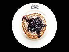 a white plate topped with pancakes covered in blueberry compote