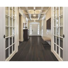 an empty hallway with wood floors and white trim on the doors, leading to another room