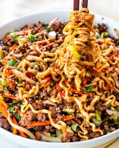 a bowl filled with noodles, meat and veggies on top of a table