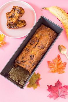 a loaf of banana bread sitting on top of a pan next to some autumn leaves