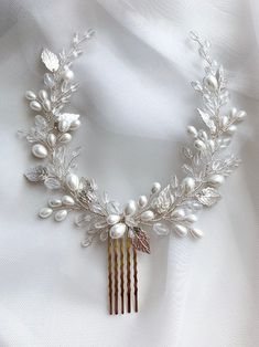 a bridal necklace with pearls and leaves on white silk background, close up photo