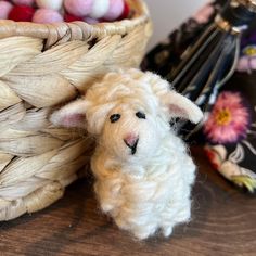 a needled sheep sitting next to a basket of yarn