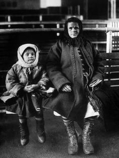 an old black and white photo of two women sitting next to each other on a bench