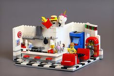 a lego kitchen with red chairs and black and white checkered flooring on the side