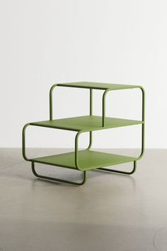 two green shelves sitting on top of each other in front of a white wall and floor