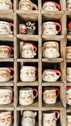 many santa claus mugs are on display in wooden crates with red handles and lids