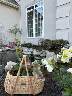 a wicker basket with flowers in front of a house on a rock garden path