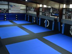 an indoor gym with blue mats and punching pads on the floor in front of them