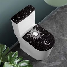 a white toilet sitting next to a plant on top of a tiled floor covered in stars and moon designs