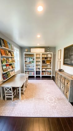 an empty room with bookshelves, tables and chairs on the floor in front of a chalkboard