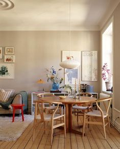 a dining room table with four chairs around it and pictures on the wall behind it