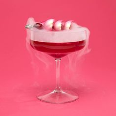 a glass filled with liquid on top of a pink surface