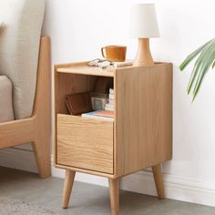 a small wooden cabinet with two drawers next to a chair and lamp on the floor