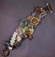 an assortment of beads and jewelry on a purple surface with a gold key hanging from it