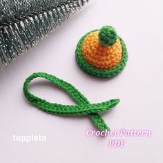 a crochet pattern for a brooch with a green leaf and orange flower