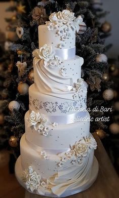 a three tiered wedding cake sitting on top of a table next to a christmas tree