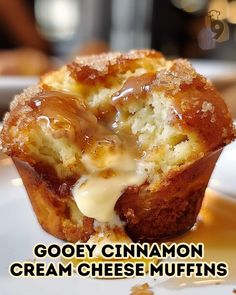 a close up of a muffin on a plate with the words gooey cinnamon cream cheese muffins