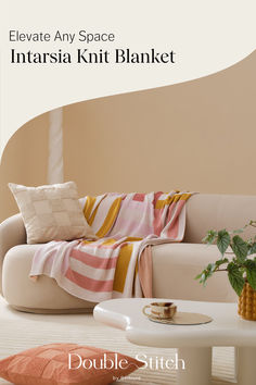 a white couch sitting next to a table on top of a hard wood floor in front of a beige wall