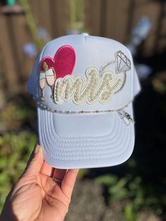 This adorable trucker hat is the perfect gift for a bachelorette or new bride! A white Otto trucker hat includes a pearl "Mrs" patch, a pink heart, champagne flutes and a sparkly diamond ring! A silver and pearl hat chain has the cutest little bride and groom dangling from it. The hat chain is removable if desired. Bride Trucker Hat With Patches, Bridesmaid Trucker Hats, Pearl Hat, Hat Chain, Bachelorette Hats, Hat Bar, New Bride, Champagne Flutes, Trucker Hats