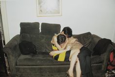 two people sitting on a couch with their arms around each other and one person hugging