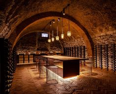 an empty wine cellar with many bottles in the wall and lights hanging from the ceiling