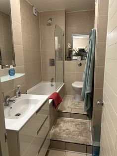 a bathroom with tiled walls and flooring next to a bathtub, toilet and sink