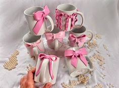 a person is holding several coffee mugs with pink bows on them