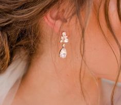 a close up of a woman's ear wearing gold earrings with flowers on them