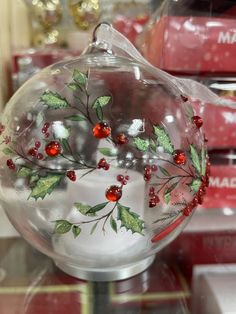 a glass ornament with holly and berries on it