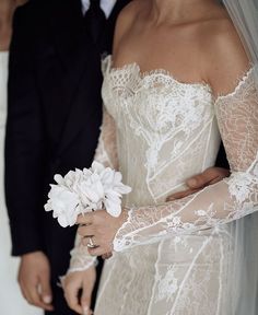 the bride and groom are dressed in black tuxedos, white laces, and veils