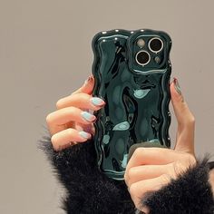 a woman holding up a cell phone case in front of her face with black and green designs on it