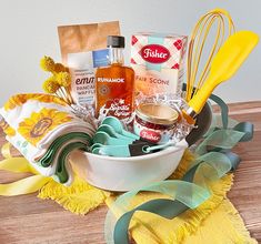 a white bowl filled with baking supplies on top of a wooden table next to a yellow towel