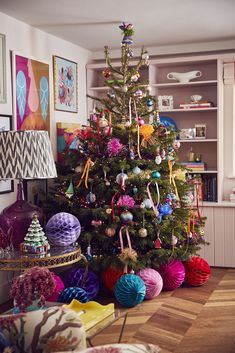 a brightly colored christmas tree in a living room with colorful ornaments on the top and bottom