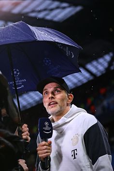 a man holding an umbrella while standing in front of a crowd at a sporting event