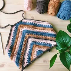 a crocheted purse sitting on top of a wooden table next to some yarn