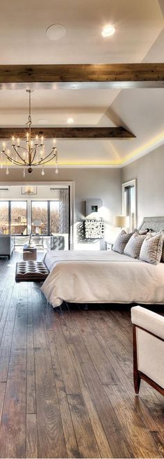 a large bedroom with wooden floors and white furniture in the room, along with a chandelier hanging from the ceiling