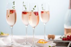 three champagne flutes with strawberries and orange slices