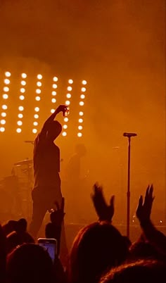 a man standing on top of a stage with his arms in the air