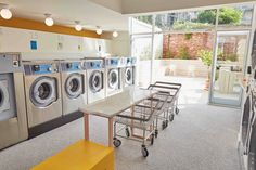 a laundry room with several washers and dryers in the corner, including a cart