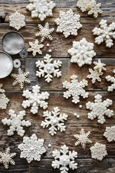 white snowflakes on a wooden table with measuring spoons and cookie tins