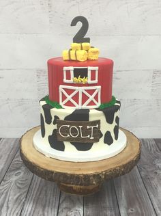 a two tiered cake with a cow theme on it's side and the number 2 on top