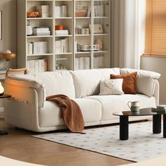 a living room with a white couch and coffee table in front of a bookshelf