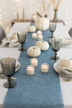 the table is set with white pumpkins and candles