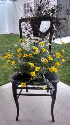 a chair sitting on top of a patio next to a planter filled with flowers