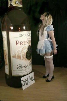 a woman standing in front of a bottle of wine with a sign attached to it