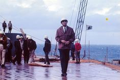 a group of men standing on top of a wooden pier next to the ocean with construction equipment