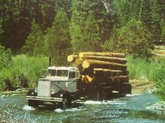 a truck driving down a river filled with lots of logs