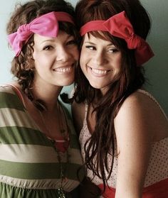 two young women standing next to each other with pink bows on their heads and one wearing a green striped shirt