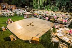 a large wooden dance floor is set up for an outdoor wedding reception in the backyard